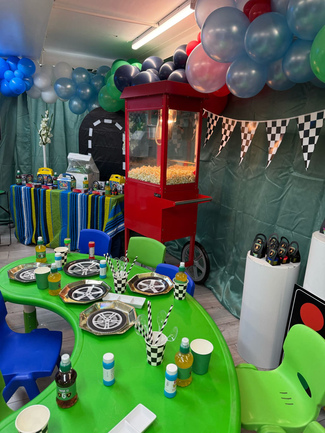 Racing-themed party table with checkered bunting & popcorn cart