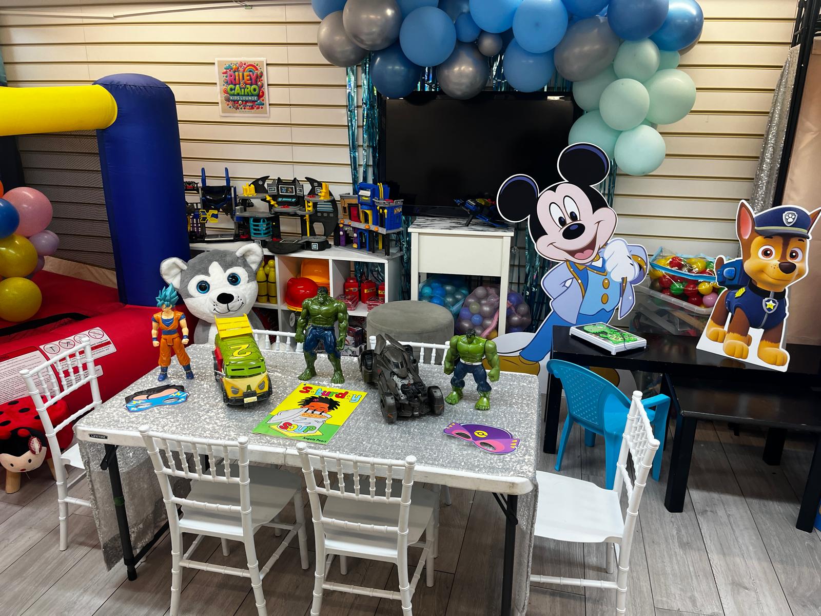 Themed kids lounge with character standees & balloon garland